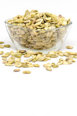 raw pumpkin seeds kernels in bowl on white background