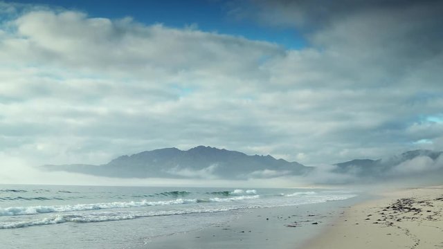 the beautiful carnota beach on the galican coast of spain on a stormy day with haze and mist hanging over the mountians and sea