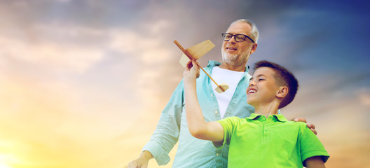 family, generation and dream concept - happy grandfather and grandson with toy airplane over evening sky