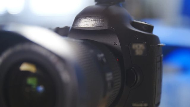Photo camera refocus from lens to body while sliding 4K. Close-up dolly slide of a professional camera in focus.