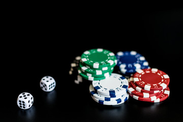dice and colored casino chips on a black background