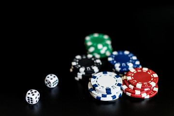 dice and colored casino chips on a black background