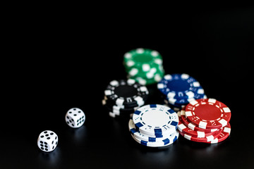 dice and colored casino chips on a black background