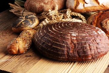 Different kinds of bread and bread rolls on board from above. Kitchen or bakery