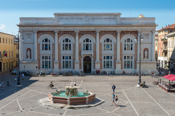 Palazzo storico nella piazza centrale di una piccola città di Pesaro in italia, si vede anche una fontana con i cavalli