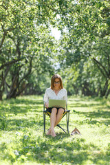 Business woman with laptop in the park sitting on a folding chair