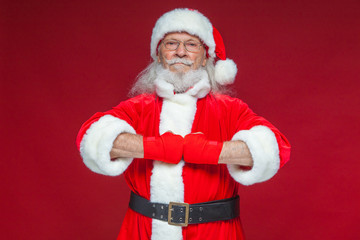 Christmas. Santa Claus with red bandages wound on his hands for boxing imitates kicks. Kickboxing, karate, boxing. Isolated on red background.