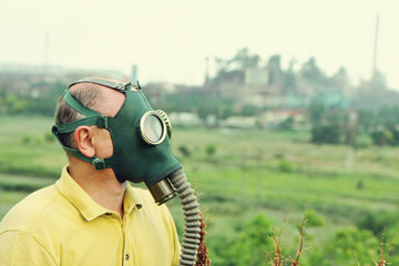 Person wearing gas mask on industrial factory background.