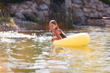 Young Caucasian girl floating with tire on swimming pond