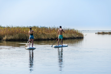 Fototapeta na wymiar Man and woman stand up paddleboarding