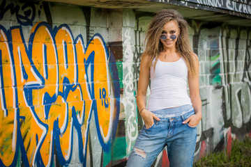 Young woman wearing street fashion cloths on graffiti background