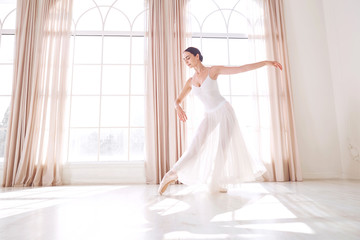 Fototapeta premium Ballerina dancing in a studio on white background window.
