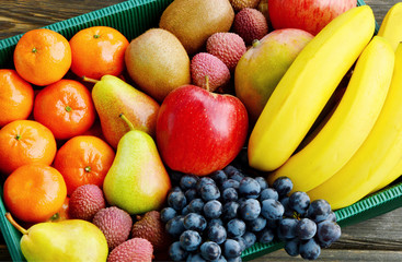 Mixed many type of winter fruits in the paper box for a gift or for transport on wooden background.