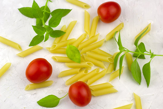 small ripe tomatoes, fresh basil and pasta   top view flat lay white concrete background
