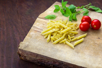 pasta,tomatoes,basil on a wooden cutting board