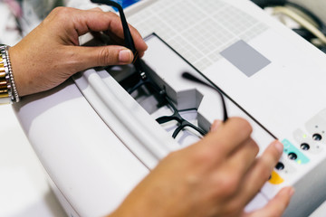 Female optician measuring and preparing glasses on the latest digital device in optical store. Professional ophthalmology instrument in clinic office and optics