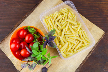 pasta,tomatoes and fresh basil leaves on a wooden cutting board