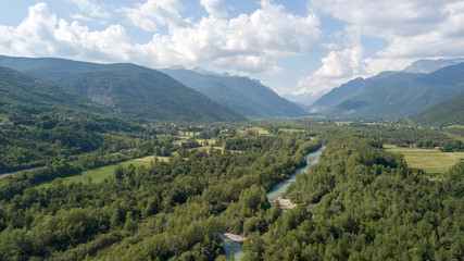 Aerial view of a river between a forest and mountains.