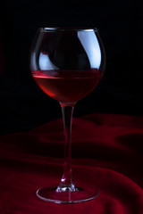 A glass of red wine on dark red background
