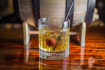 Cocktail with cherry in front of barrel