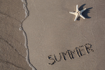 Starfishes and wave with SUMMER text on sand beach
