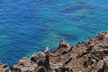 The crystal clear sea water and coral reef under the surface with rock foreground