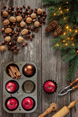 Christmas  background with fir tree branches, red apples, walnuts, hazelnut, nutcracker, cinnamon and red candles.