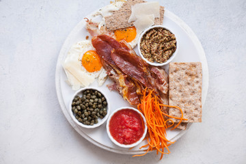 Breakfast plate fried egg, crispy bacon tomatoes in a white plate mustard tomato sauce 