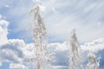Splashes of water from a fountain against the blue sky