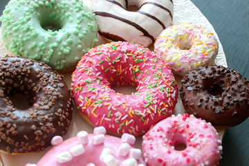 Photos of different donuts. Assorted colorful donuts in pink, green, chocolate icing close-up, sweet dessert.