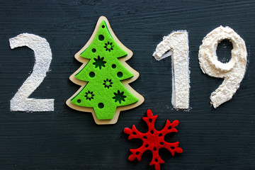 Text 2019 on a black background, a green felt tree instead of the number 0. The inscription is isolated, free space for your text. Christmas and new year
