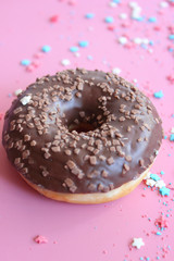 Chocolate-covered doughnut  on bright pink background close-up