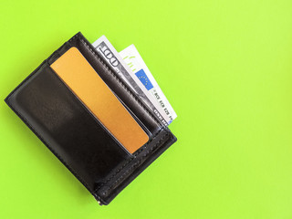 Black leather wallet with dollar bills and a gold card.