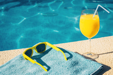 Sunglasses, towel and juice on board the pool - holiday attributes