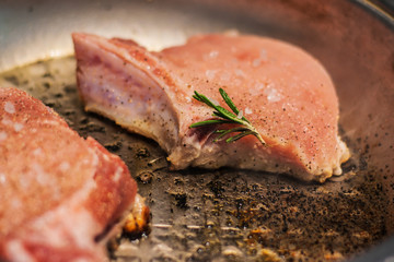 Marinated pieces of pork loin on a bone fry in a frying pan