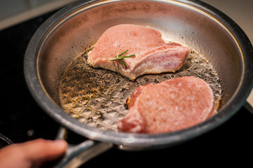 Marinated pieces of pork loin on a bone fry in a frying pan