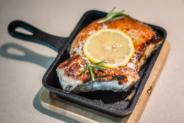 Marinated pieces of pork loin on a bone are fried in a small frying pan