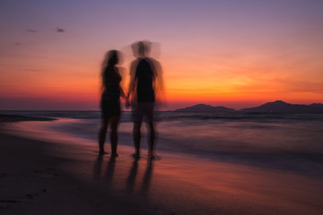 Blurry couple on the beach watching sunset