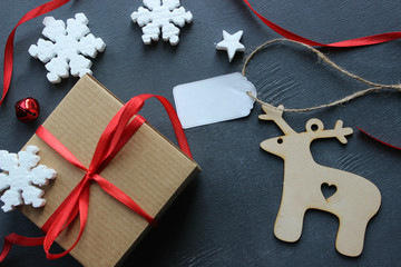 Christmas composition. Gift box with red satin ribbon, tree and snowflakes on black background. Christmas decor. Extensive series of holiday shots with a variety of props and backgrounds. Lots of copy