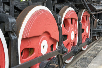 Red large iron wheels of an old vintage locomotive on railroad close-up. Wheels of a locomotive. Large wheels.