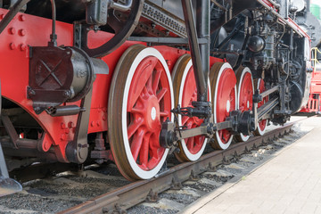 Red large iron wheels of an old vintage locomotive on railroad close-up. Wheels of a locomotive. Large wheels.