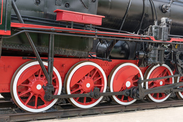 Red large iron wheels of an old vintage locomotive on railroad close-up. Wheels of a locomotive. Large wheels.