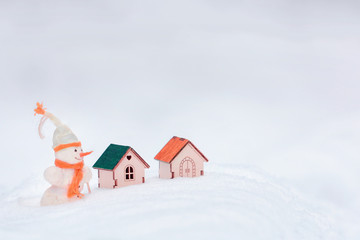 Realtor snowman, сhristmas scene. Funny seller of real estate near the small wooden toy houses