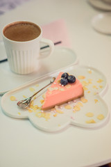 Dessert: pink cheesecake on a white cloud dish, next to a mug of hot chocolate