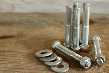 group of bolts with nuts and washers close up on a wood background with writing space