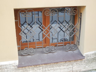 The basement window with a beautiful lattice of geometric shape and its shadow on the glass