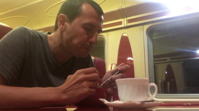 man at night eating soup in the train restaurant railway cat drinks coffee. man lifestyle on the train concept journey travel railway