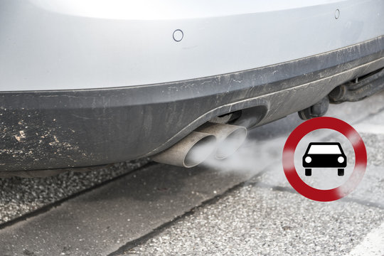 Double Exhaust From A Car With Smoke And The Traffic Sign For Driving Ban, In German Fahrverbot For Diesel Motor Vehicles In Low Emission Zones Of Some Cities In Germany