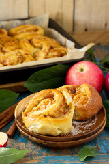 Fresh Homemade Rolls Buns with apples and cinnamon in glaze on a blue vintage wooden background.