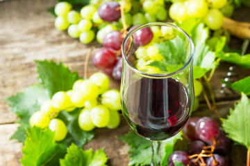 Wine background. Red wine in glasses, bottle, grapes on vintage background, wine concept. Copy space.